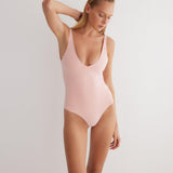 "Model wearing the Agneta Orange/Pink reversible bodysuit from the front, showcasing its modern design with a scoop neckline and body-hugging fit. "
