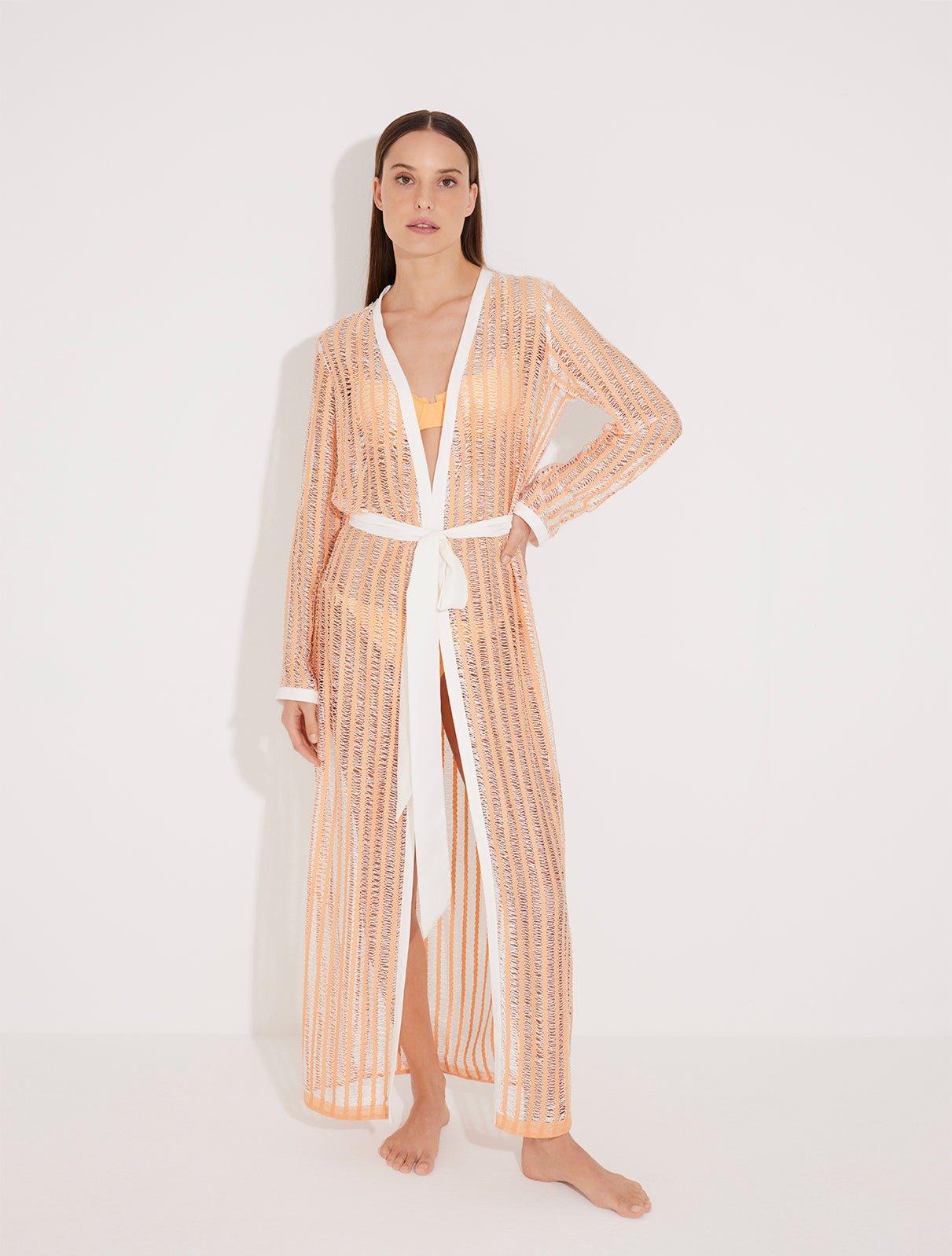 "Front view of the Aitana Orange/White Kaftan, showcasing its ankle-length cut, long sleeves, and crisscross knitted pattern. "