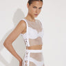 "Model wearing Alejandra White Rhinestone Crop Top from the front, highlighting high neck and side tie details."