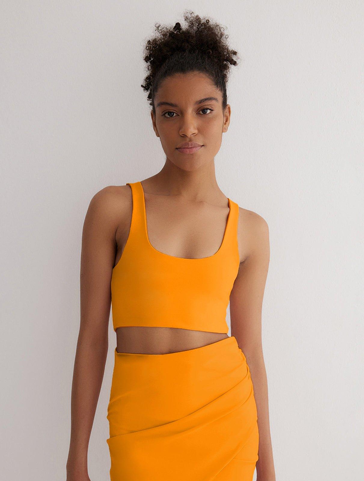 "Front view of a model wearing Alva Orange/Pink Crop Top, showcasing the scoop neckline and sleek fit."