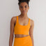 "Front view of a model wearing Alva Orange/Pink Crop Top, showcasing the scoop neckline and sleek fit."