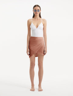 Model displaying the Antonia brown satin skirt from the front, showcasing its elegant wrap-style design and slim fit that accentuates the waist and enhances the natural silhouette."