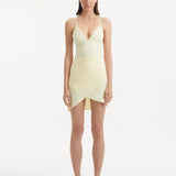 Model showcasing the Antonia yellow skirt from the front, highlighting its graceful wrap-style and slim-fit design that contours the body with an adjustable and tailored fit.