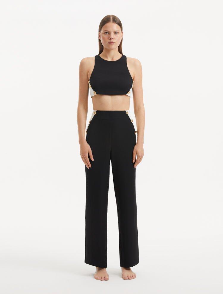 "Model showcasing the Augustine Black/White Pants from the front, highlighting the stylish cropped cut and one-shoulder design."