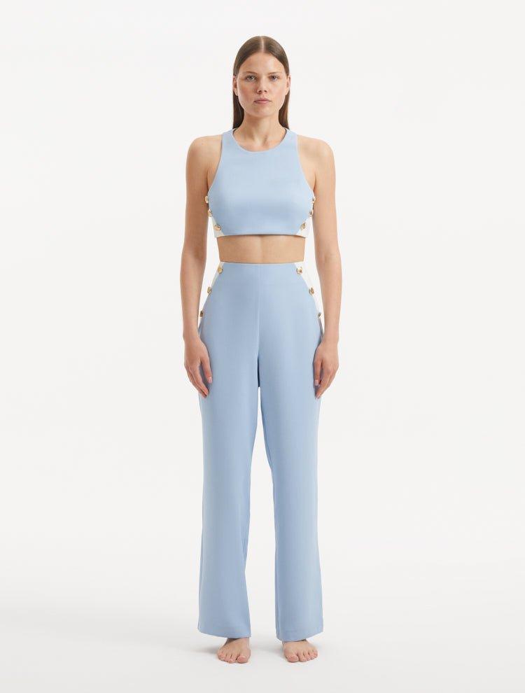 "Model showcasing the Augustine White/Baby Blue Pants from the front, highlighting the chic cropped silhouette and one-shoulder design."