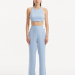 "Model showcasing the Augustine White Baby Blue Top and Wade Pants from the front, highlighting the chic cropped silhouette and one-shoulder design."