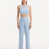 "Model showcasing the Augustine White Baby Blue Top and Wade Pants from the front, highlighting the chic cropped silhouette and one-shoulder design."