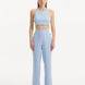 "Model showcasing the Augustine White Baby Blue Top and Wade Pants from the front, highlighting the chic cropped silhouette and one-shoulder design."