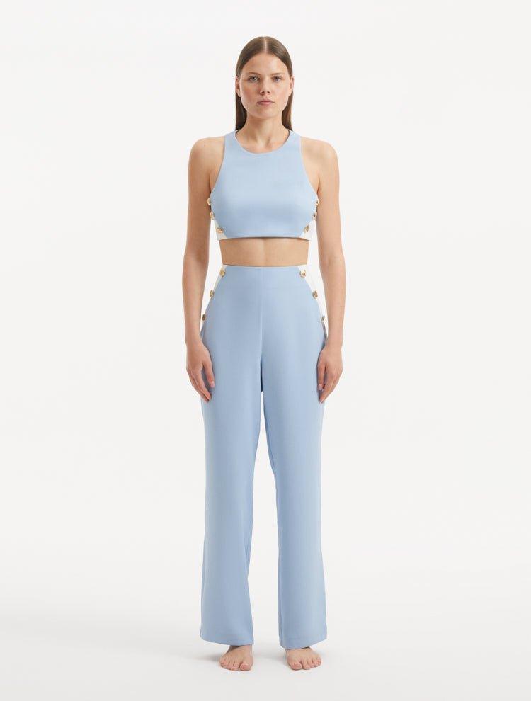 "Model showcasing the Augustine White Baby Blue Top and Wade Pants from the front, highlighting the chic cropped silhouette and one-shoulder design."