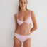 "Model Wearing from Front: Model showcasing the Aya pink bikini bottom from the front, highlighting the low-rise hipster design and medium coverage."