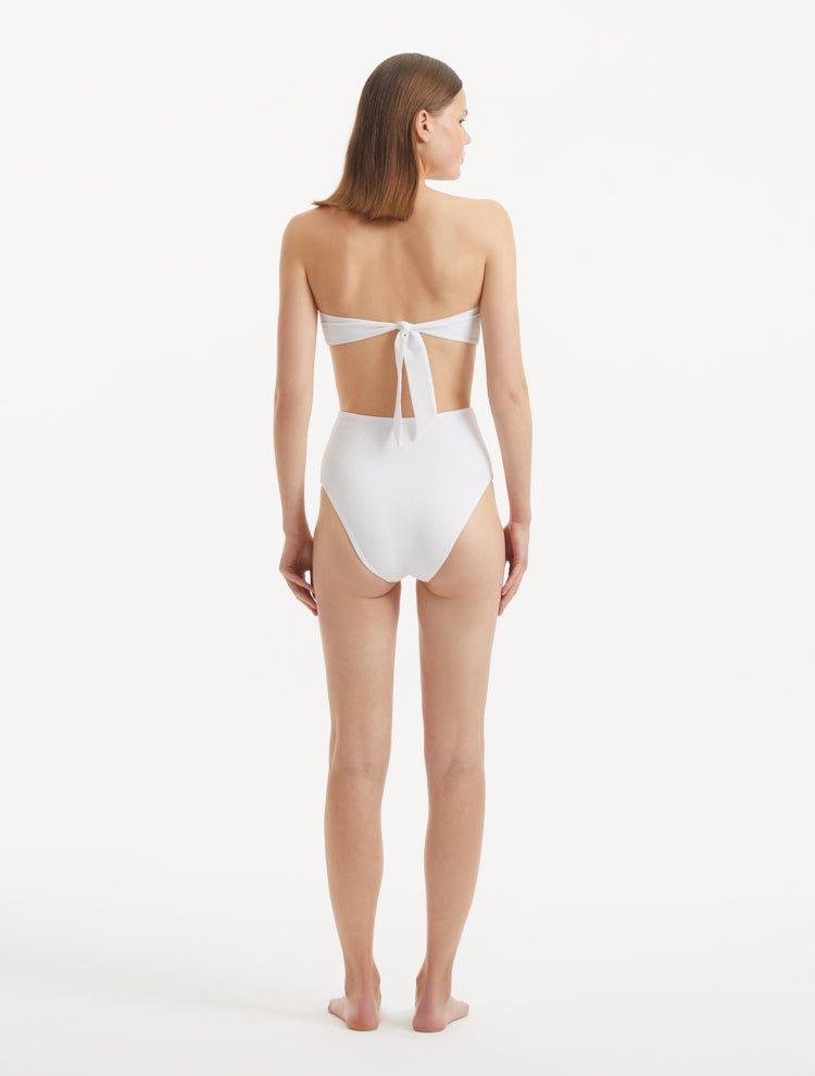 Model displaying the Baia White Bikini Set from the back, focusing on the luxe gold clasps and the seamless fit of the bikini bottom.