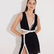 "Model wearing Blanca Black/White Asymmetrical Dress with gold button accents."