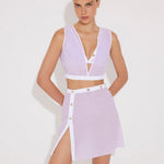 "Model wearing Blanca Lilac/White Asymmetrical Dress with gold button accents."