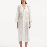 Model wearing the Blaze white kaftan from the front, showcasing its V neckline, enchanting wavy details, and ankle-length design. The self-tie belt accentuates the waist, providing a flattering and adjustable fit.