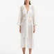 Model wearing the Blaze white kaftan from the front, showcasing its V neckline, enchanting wavy details, and ankle-length design. The self-tie belt accentuates the waist, providing a flattering and adjustable fit.
