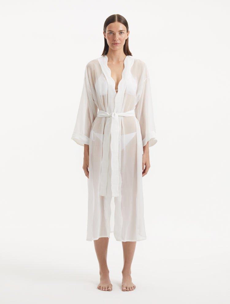 Model wearing the Blaze white kaftan from the front, showcasing its V neckline, enchanting wavy details, and ankle-length design. The self-tie belt accentuates the waist, providing a flattering and adjustable fit.