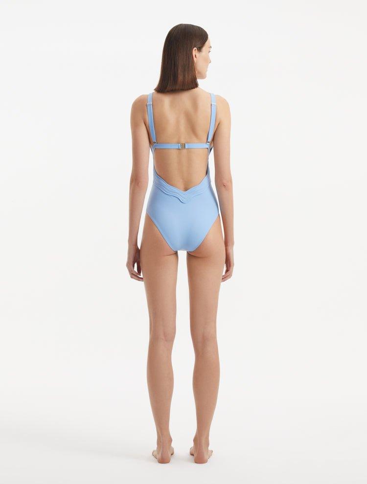 Back view of Breena Baby Blue Swimsuit, highlighting low-back cut and gold clasp detailing.