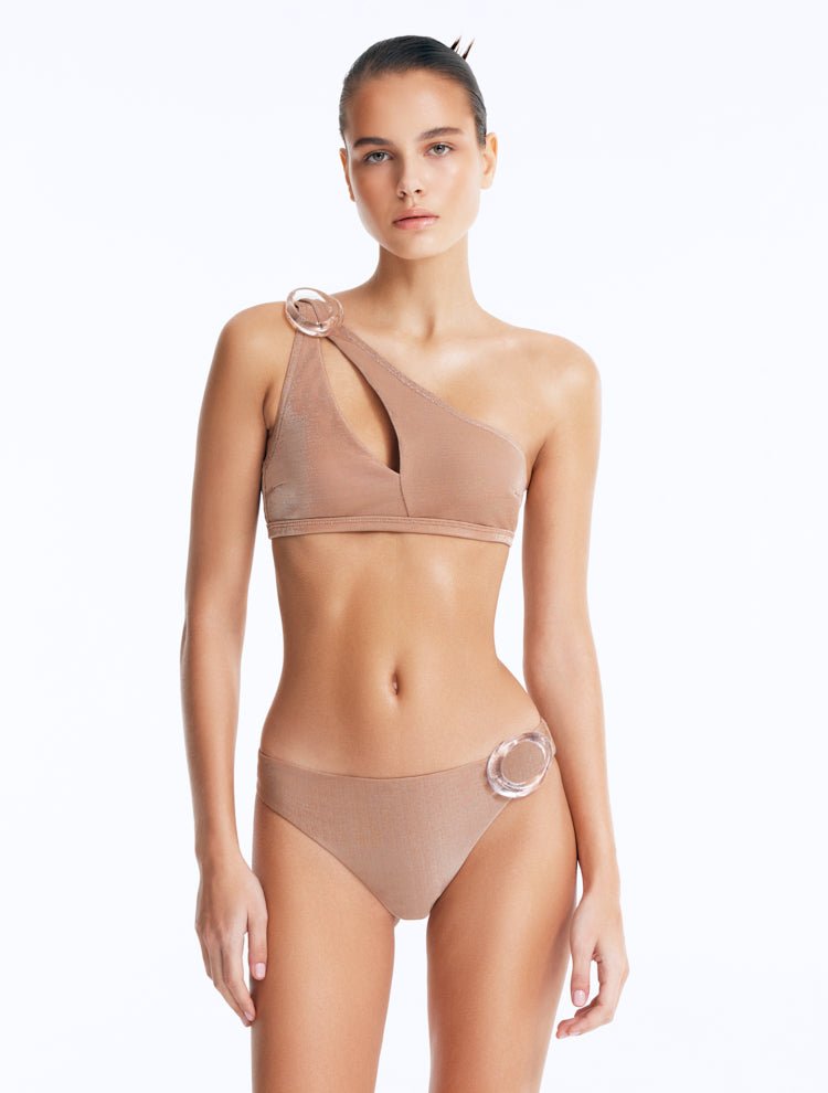 Front View: Model in Calix Bronze Bikini Top - One Shoulder, Fully Lined, Chic, Metallic Fabric, Clear Glass Hoop Accessory Detail, MOEVA Luxury Swimwear