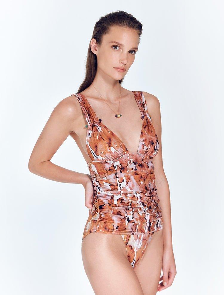 "Front View: "Carina Floral Abstract Swimsuit featuring a V-neckline, ruched band under the bust, and decorative amethyst and aventurine stones on the shoulder straps."