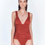 "Model wearing the Carina Red Ochre Swimsuit from the front, showcasing the V-neckline and ruched band under the bust."