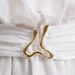 "Close-up of the Dante White Dress’s unique gold sculpted accessory, reflecting its nature-inspired design."