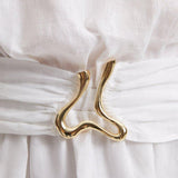 "Close-up of the Dante White Dress’s unique gold sculpted accessory, reflecting its nature-inspired design."