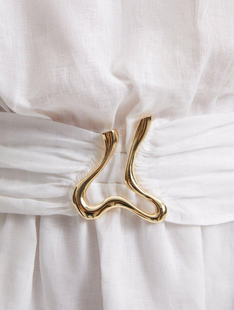 "Close-up of the Dante White Dress’s unique gold sculpted accessory, reflecting its nature-inspired design."