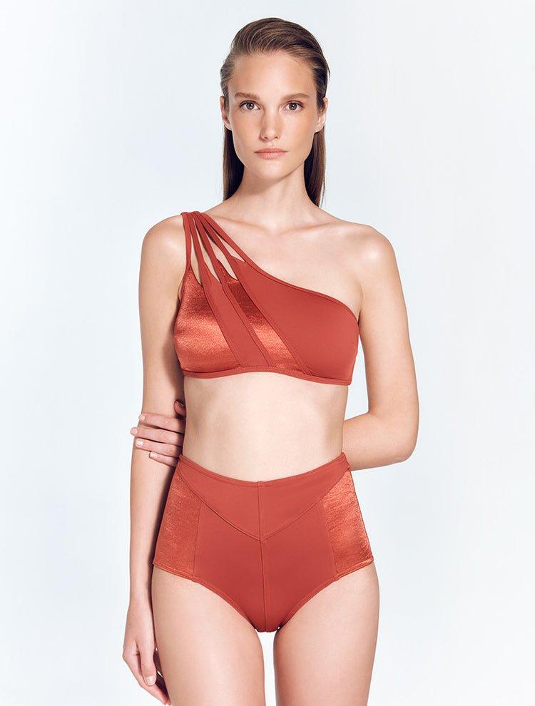 "Front view of the Darika Red Ochre Bikini Top, showcasing the geometric one-shoulder design with cutout details and contrast panels."