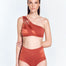 "Front view of the Darika Red Ochre Bikini Top, showcasing the geometric one-shoulder design with cutout details and contrast panels."