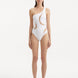Model showcasing the Delta White Swimsuit, highlighting the one-shoulder design and asymmetric cutouts.