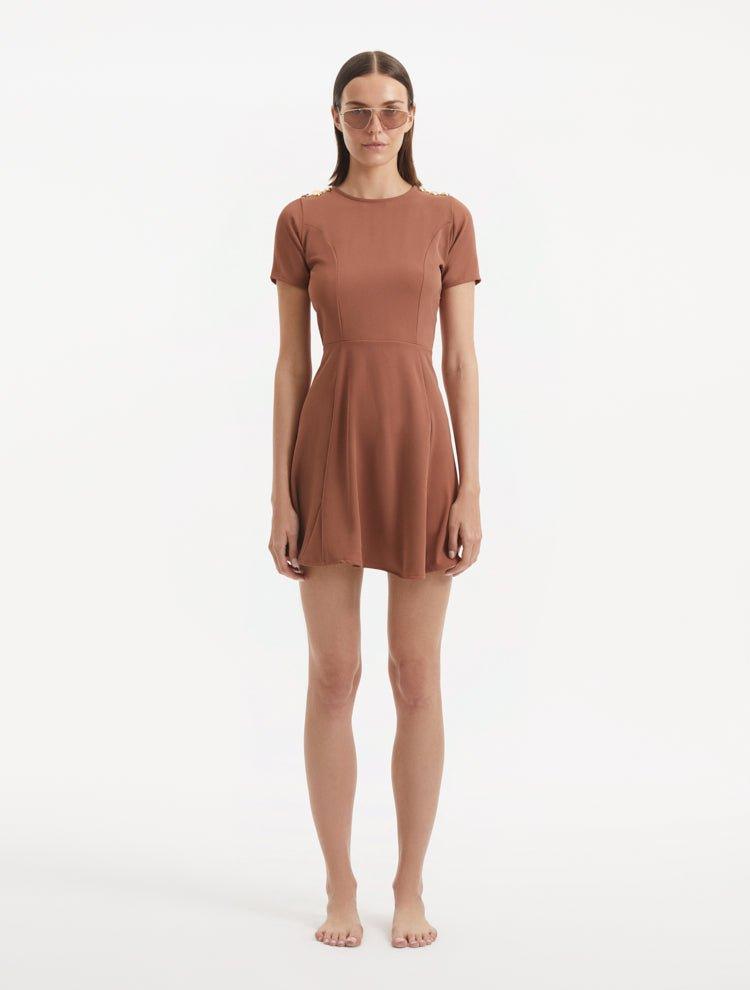 "Model wearing the Derin Brown Dress from the front, highlighting the knee-length cut, short sleeves, and shell-shaped gold buttons."