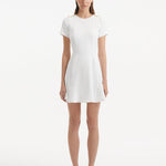 "Model wearing the Derin White Dress from the front, showcasing the knee-length cut, short sleeves, and shell-shaped gold buttons."