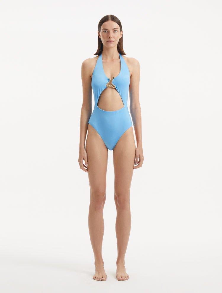 Model wearing the Dwyn Baby Blue Swimsuit, highlighting the tie-neck design and gold sculpted accessory.