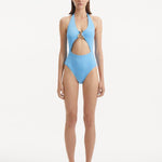 Model wearing the Dwyn Baby Blue Swimsuit, highlighting the tie-neck design and gold sculpted accessory.