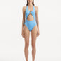 Model wearing the Dwyn Baby Blue Swimsuit, highlighting the tie-neck design and gold sculpted accessory.