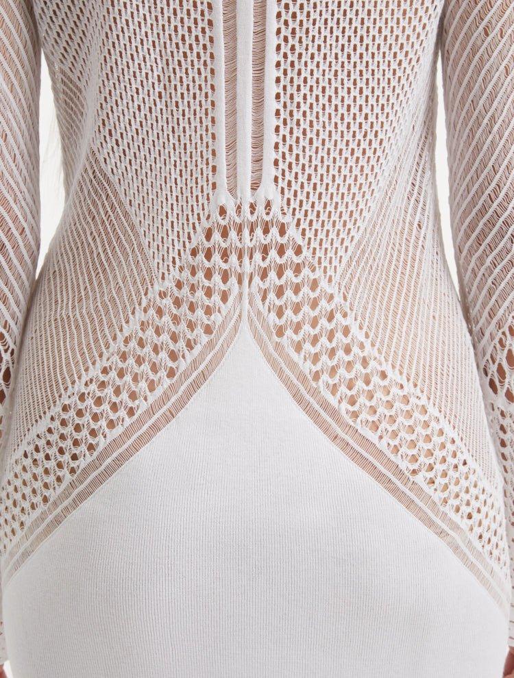 Close-up of the Elba white dress’s knitted fabric and fringe details, showcasing the intricate texture and craftsmanship. The semi-sheer panels on the sleeves add a touch of modern elegance