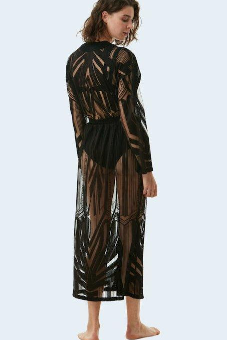 "Model wearing Electra Black Kaftan from the back view, highlighting the sheer, flowing fabric and the adjustable strappy belt that cinches the loose fit."