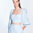 "Model wearing Eliana Baby Blue Top with square neckline, blouson sleeves, and adjustable lace-up back, paired with high-waisted pants"