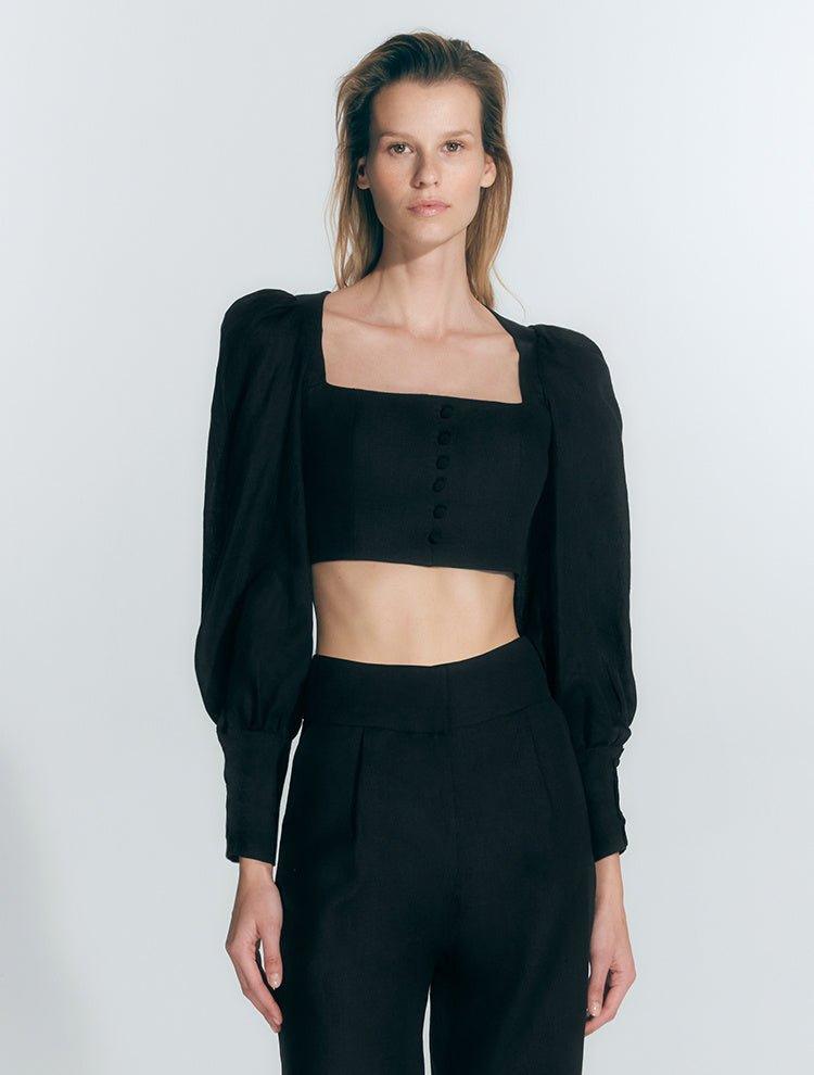 "Model wearing Eliana Black Top with square neckline, cropped silhouette, and blouson sleeves with buttoned cuffs."