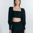 "Model wearing Eliana Black Top with square neckline, cropped silhouette, and blouson sleeves with buttoned cuffs."