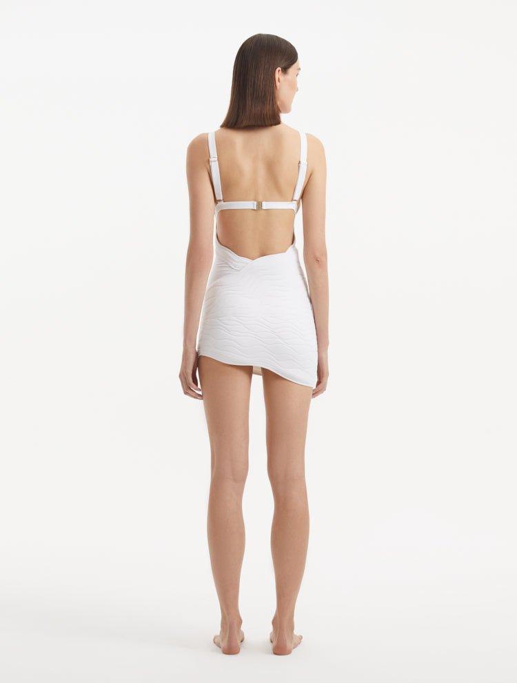 "Back view of the Ephram white high-waist asymmetric skirt, featuring the high-waisted design and unique asymmetric cut. The wavy texture detail adds visual depth and sophistication."