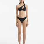 Model wearing the Eyre Black Bikini Bottom, highlighting the mid-rise hipster design and shell-shaped gold button details.