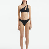 Model wearing the Eyre Black Bikini Bottom, highlighting the mid-rise hipster design and shell-shaped gold button details.