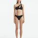 Model wearing the Eyre Black Bikini Bottom, highlighting the mid-rise hipster design and shell-shaped gold button details.