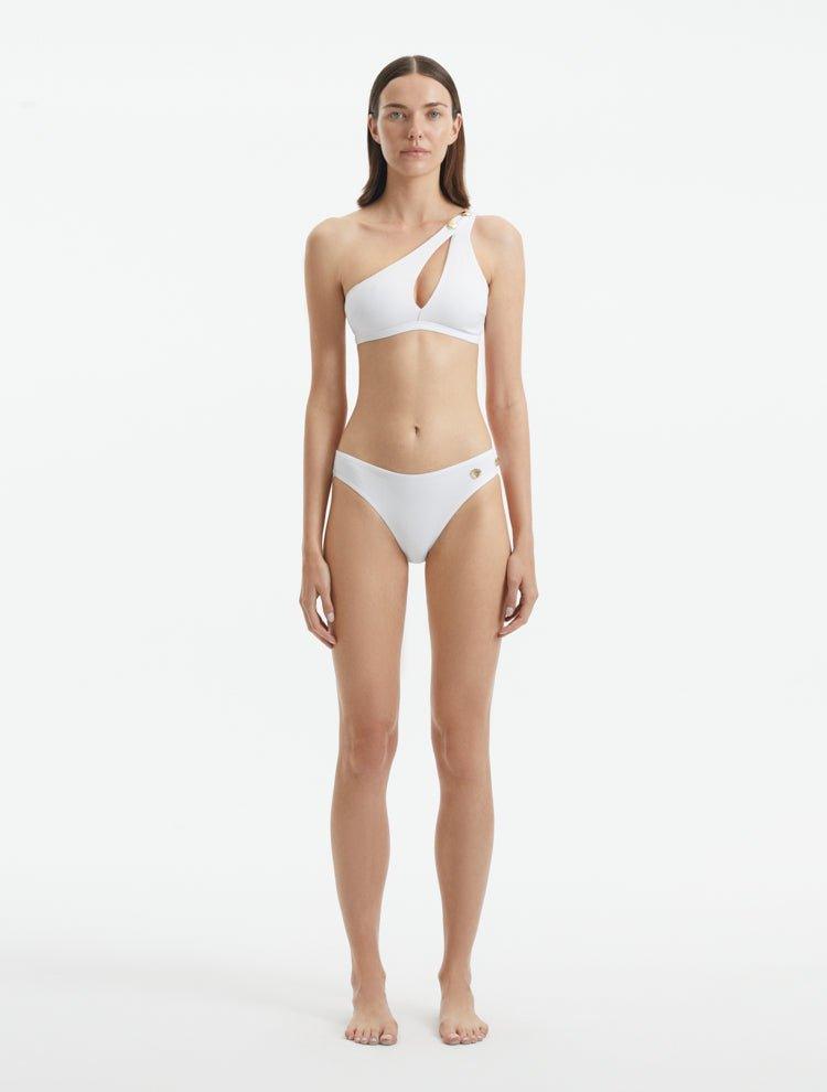 Model wearing the Eyre White Bikini Set, highlighting the mid-rise design and shell-shaped gold button details.