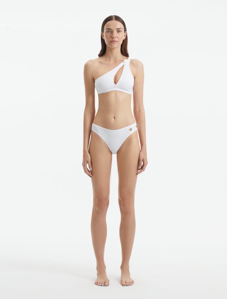 Model wearing the Eyre White Bikini Top, highlighting the one-shoulder design and shell-shaped gold buttons.