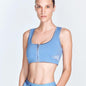 "Fanny Blue Sports Bra front view showcasing the square neck, satin matte contrast, and front zip detail. "