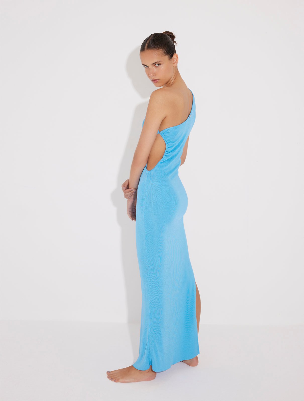 "Back view of the Fewa Blue One-Shoulder Knitted Dress revealing the elegant cut and high-shine viscose material, perfect for formal occasions and summer festivities."