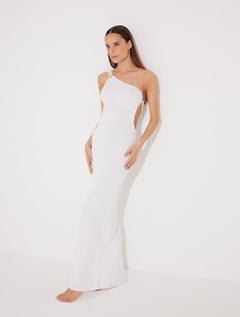 Front View: Model in Fewa White Dress - MOEVA Luxury Swimwear, One Shouldered Ready to Wear Dress, Gold Sculpted Hoop Accessory, Side Slit, MOEVA Luxury Swimwear