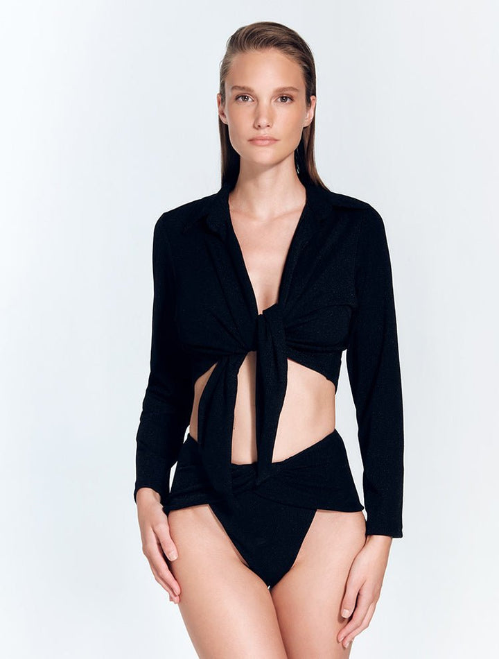 Front View: Model in Greta Shiny Black Shirt - MOEVA Luxury Swimwear, Cropped Silhouette, Made of Swimwear Fabric, Tie at the Front, Unlined, Comfort and Day to Night, MOEVA Luxury Swimwear